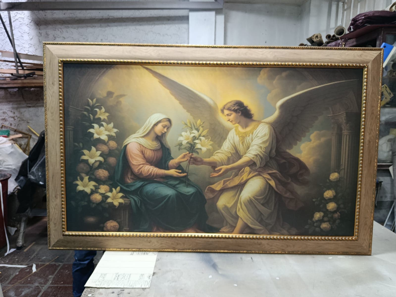 Cuadro de la Anunciación con marco dorado en taller