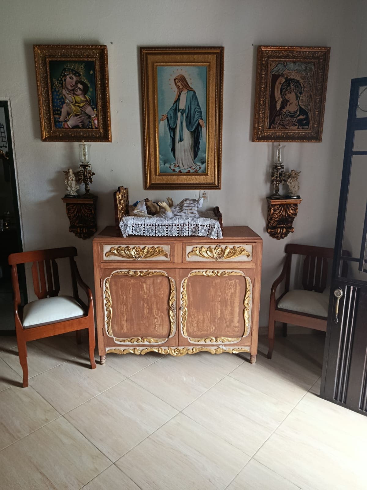 Consola dorada con cuadros religiosos enmarcados